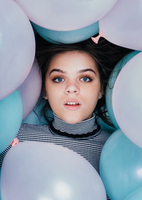 headshot of a person surrounded by pastel colour balloons