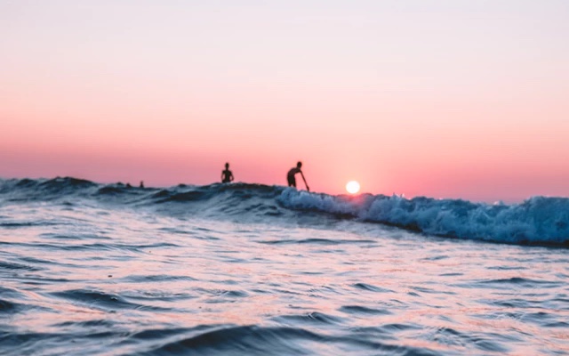 people surfing on big waves at sunset